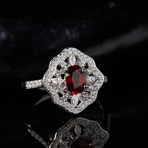 Macro shot of S925 silver ring with red oval garnet and surrounding white diamonds
