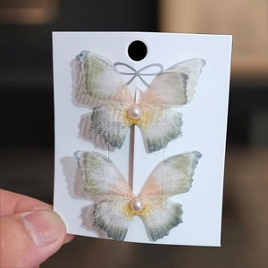 Detail of gradient tulle butterfly hair clips with central pearl on white display card