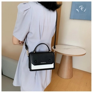 Detail view of contrast stitching leather shoulder bag worn by model in a modern interior