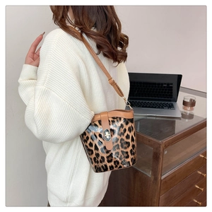 Detail of leopard print bucket bag with metal twist lock and brown leather strap
