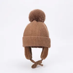 Detailed view of brown winter knit hat with fluffy pom pom and warm fleece lining