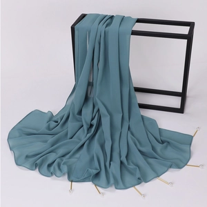 Close-up of teal chiffon shawl with elegant pearl accents and gold pins on black frame
