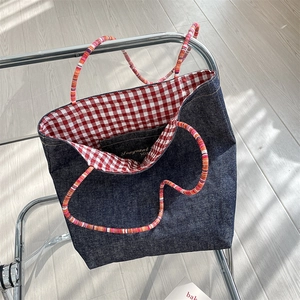 Close-up of a vintage denim tote bag featuring red gingham lining and thin straps