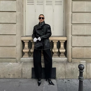 Style de rue d'une femme en veste en cuir noire oversize et pantalon à jambes larges