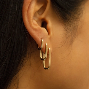 Set of three classic golden U-shaped hoop earrings in different sizes worn by a model
