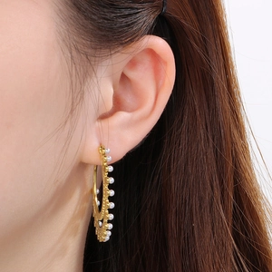 Close-up of model wearing large double-layer gold earrings with pearl accents