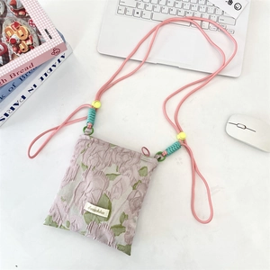 Close-up of jacquard floral crossbody bag with adjustable rope strap and branded woven label