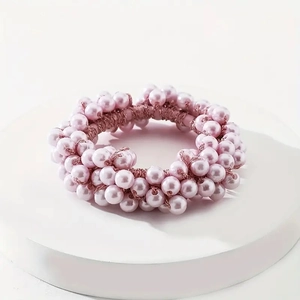 Close-up of handmade pink faux pearl elastic hair tie on a white podium surface