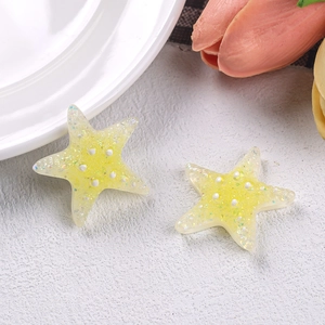 Macro shot of yellow glittery resin starfish charms for DIY hairpins and accessories