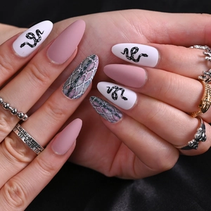 Long almond press-on nails with matte pink and snake skin patterns on black silk