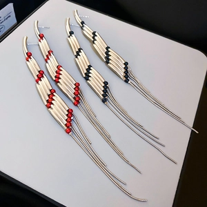 Detail of elegant rectangular tassel earrings in silver finish with red and black beads