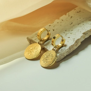 Vintage gold evil eye hoop earrings with engraved mystical symbols on stone surface