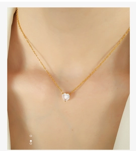 Close-up of elegant gold chain necklace with a heart-shaped zircon pendant on a model