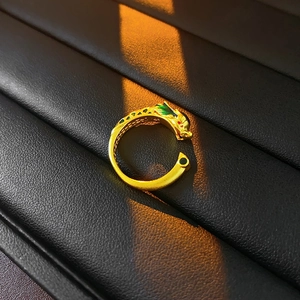 Close-up of golden dragon head ring with colorful enamel details on textured black leather