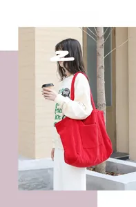 Detailed view of red corduroy tote bag featuring wide-wale texture and large front pocket