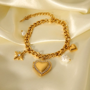 Nahaufnahme vom goldenen Panzerarmband mit Diamantherz-Anhänger und Perlendetails