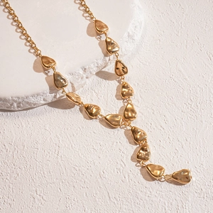 Detail of gold irregular lava-textured pendant necklace on white stone display