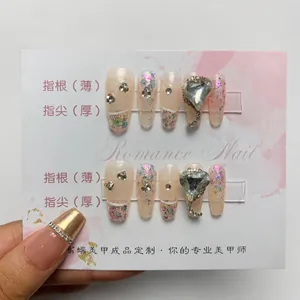 Detailed view of handmade press-on nails with pink smudge, shell foil, and heart crystal