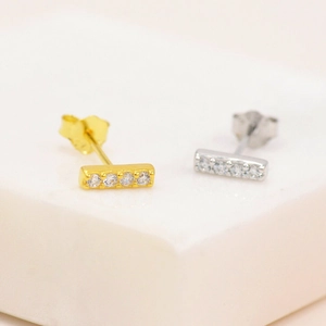 Detail of gold and silver rectangular stud earrings with five small cubic zirconia stones