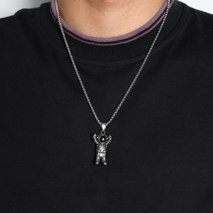 Close-up of titanium astronaut pendant necklace worn by model showing hip-hop style detail