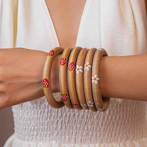 Close-up of wooden bangles with hand-painted strawberry and daisy floral patterns