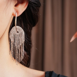Gros plan de boucles d'oreilles à pompons argentés avec strass portées par un mannequin