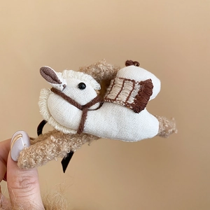 Detail of white fabric rocking horse hair claw clip with cozy beige plush base lining
