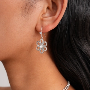 Detailed close-up of sparkling flower-shaped earrings with diamond accents on model