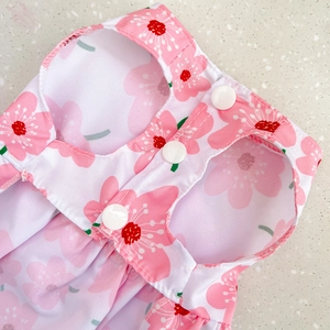 Close-up of pink cherry blossom pet dress with three white snap buttons and fabric detail