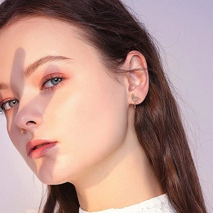 Close-up of elegant rose gold flamingo stud earring with pavé zircon worn on ear