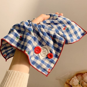 Blue gingham scrunchie with cherry print and red button detail on model hand