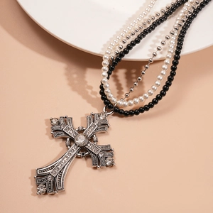 Close-up of a layered necklace featuring a rhinestone cross pendant and faux pearls