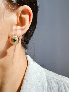 Macro close-up of French vintage gold brushed earrings with green gem and zircon details
