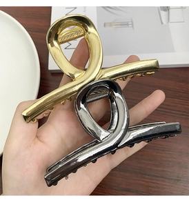 Detail of gold and gunmetal finish metal hair claw clips held in hand for hairstyling
