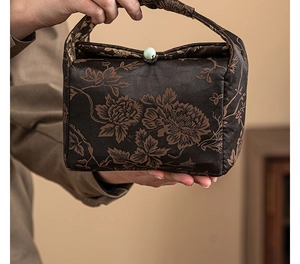 Close-up of a brocade tea caddy bag with peony embroidery and a jade button closure