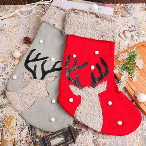 Plush Christmas reindeer stockings in red and gray on festive snow wood surface
