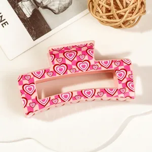 Detail of pink checkerboard hair claw clip with red heart patterns and strong grip teeth