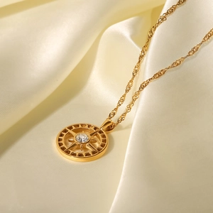 Detailed close-up of a gold compass pendant with a zircon center on silk fabric