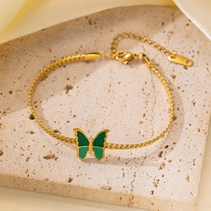 Detalle de pulsera de cadena de serpiente dorada con colgante de mariposa verde