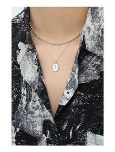 Detail of layered S925 sterling silver necklaces featuring an oval tulip pendant on model