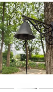 Detail of vintage cast iron garden doorbell with scrolling bracket mounted on a tree
