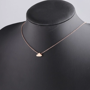 Detail of rose gold cloud pendant necklace on a black jewelry display stand
