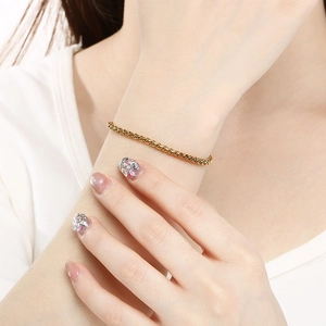 Gros plan d'un élégant bracelet chaîne panier en acier inoxydable doré porté au poignet