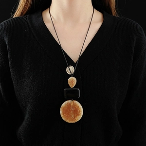 Brown marble resin teardrop necklace with embossed coin pendant on a black sweater