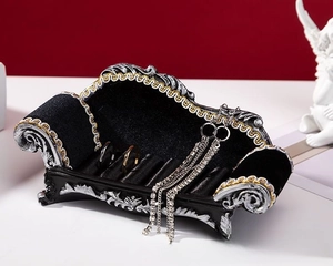 Macro view of black velvet sofa jewelry box with silver trim holding rings and earrings