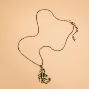 Macro shot of an antique bronze scorpion pendant necklace on a soft orange background
