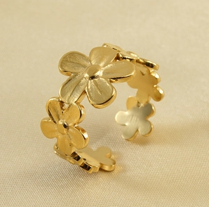 Detalle lateral de anillo floral de oro 18k con flores mate sobre seda color champán