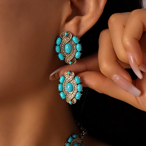 Close-up of retro gold-toned earrings with turquoise stones and shimmering rhinestones