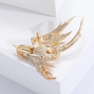 Detailed back view of golden phoenix brooch showing metal texture and pin fastener