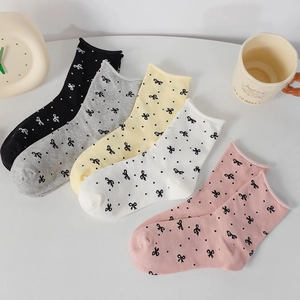 Close-up of five pairs of cotton polka dot socks with bows in various soft colors